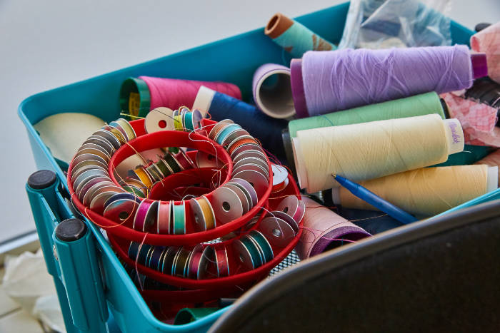 Colorful Thread Spools And Bobbins In Sewing Bin, Craft Room View